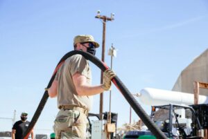 Airman handling large pipe feeding cryogenic rocket propellants for liquid rocket CONOPS and novel deployable systems tests.