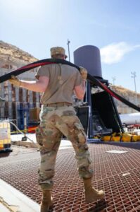 Airman handling large pipe feeding cryogenic rocket propellants for liquid rocket CONOPS and novel deployable systems tests.