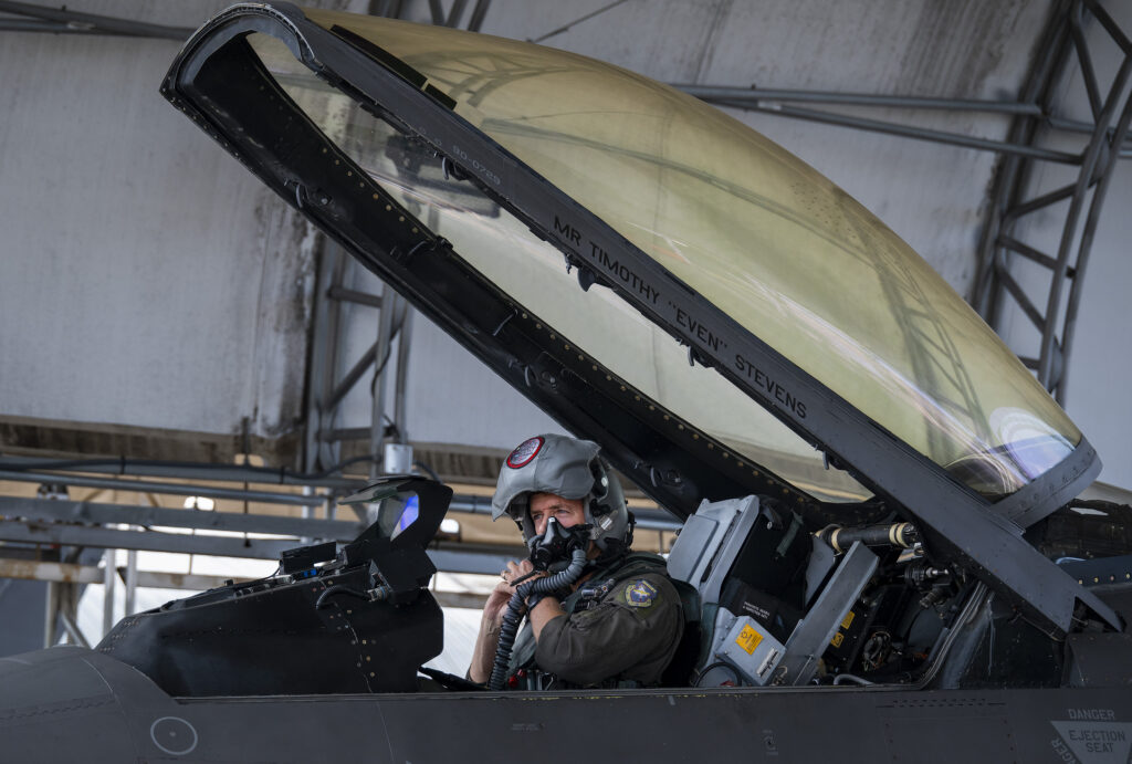 Airmen adjusts a breathing mask as he gears up for a test flight in an F16 as part of the VENOM Program.