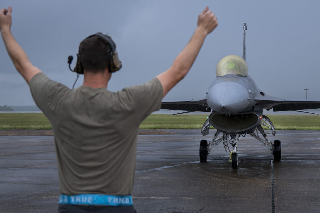 Aircraft Marshaller aids in taxying a readied F-16 aircraft.