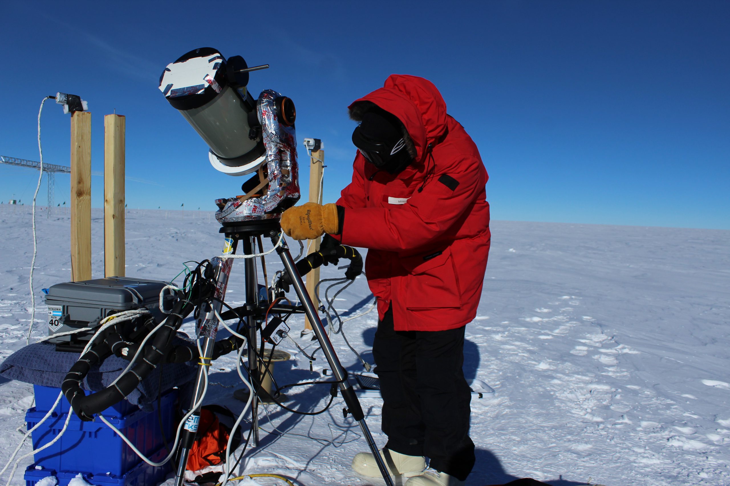 Researcher working on telescope at south pole. The ground is snowy.