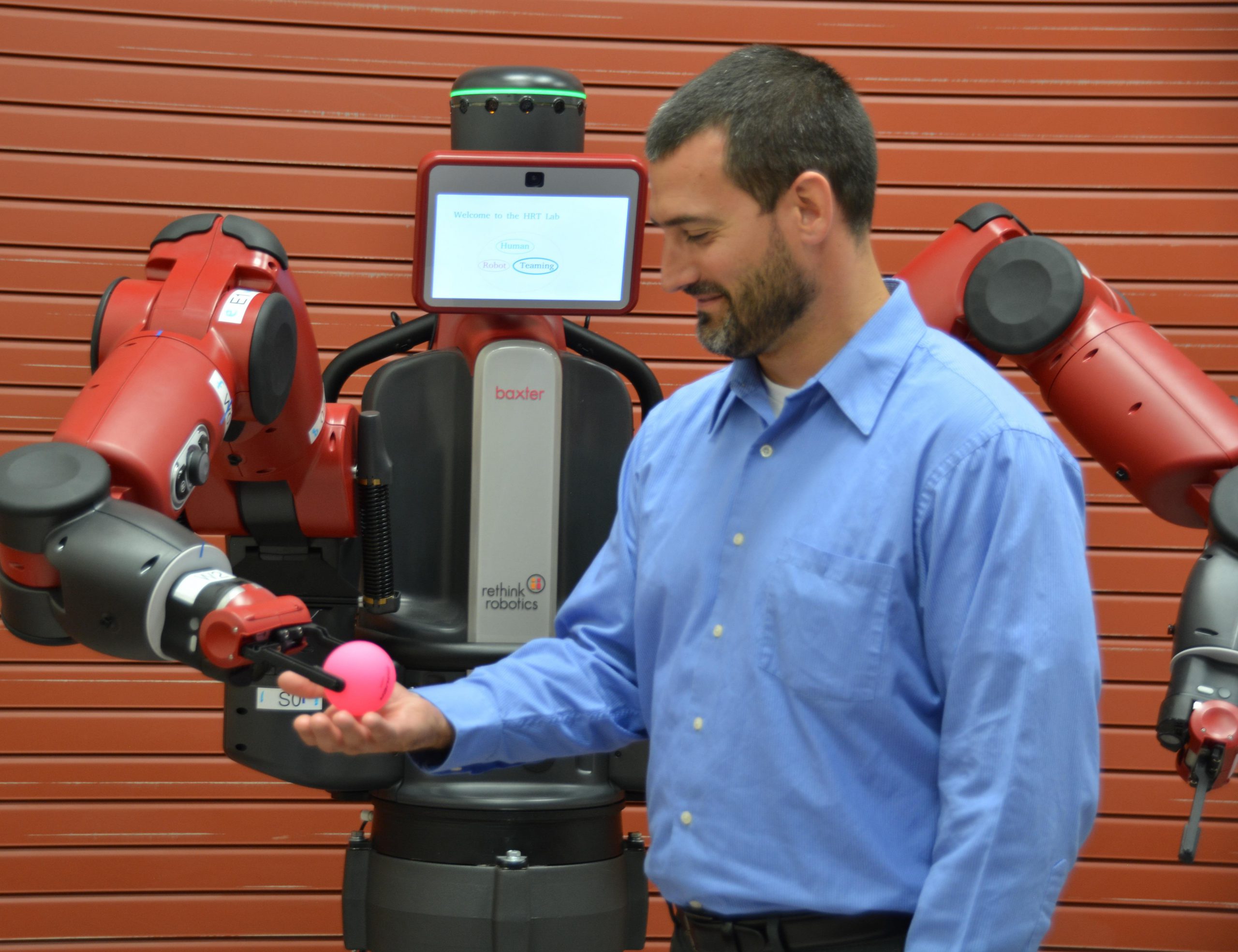 Dr. Joseph Lyons, Human Trust and Interaction Branch technical advisor, is given a ball by the Baxter robot after instructions were given to the robot by a member of Lyons' team.