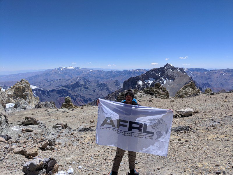 Researcher holding AFRL Flag on Mountain