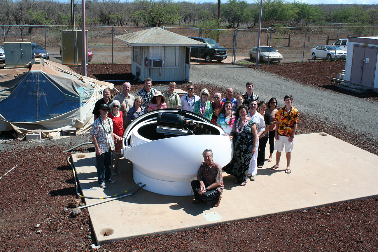 team posing for photo next to program telescope