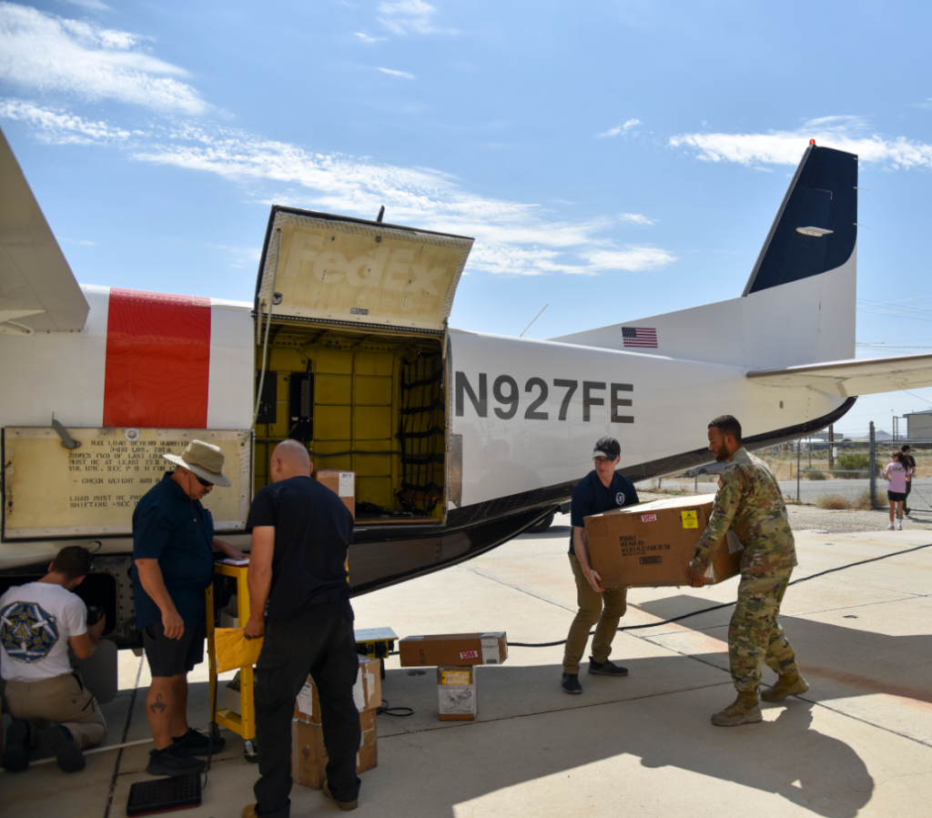 An Airman in fatigues alongside a number of plain clothes team members load up the test Cessna aircraft.