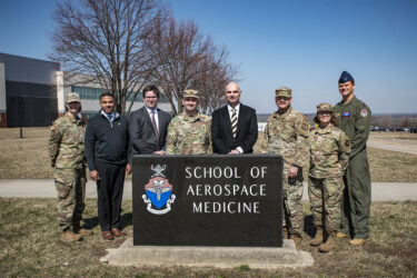 leaders from USAFSAM and Purdue posing around a USAFSAM outdoor sign