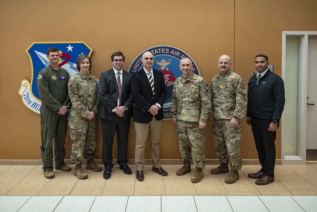 leaders standing in-front of 711 HPW wall display